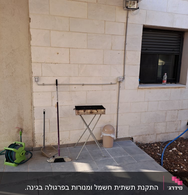 כבל חשמל ירוק מגולגל על גלגלת ליד קיר לבנים.